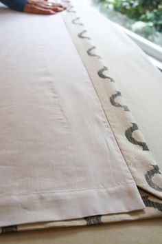 a person laying on top of a bed with a white sheet and black trim around it