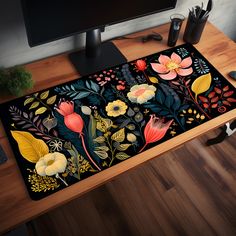 a desk with a computer monitor, keyboard and flower rug on top of the desk