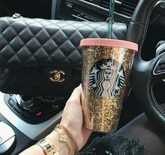 a woman holding a starbucks cup in her hand while sitting in the drivers seat of a car