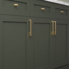 a kitchen with green cabinets and white counter tops, gold pulls on the handles that are brass