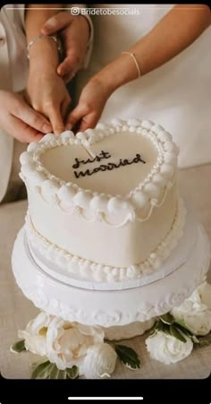 a bride and groom cutting their wedding cake with the word happy married written on it