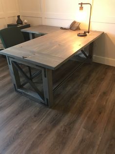 a wooden table sitting on top of a hard wood floor next to two green chairs