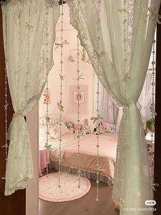 a bedroom decorated in pink and white with beaded curtains