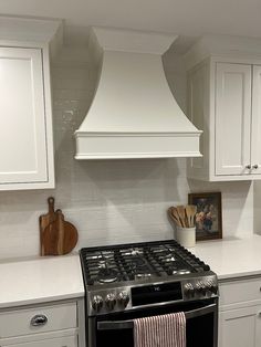 a stove top oven sitting inside of a kitchen next to white cabinets and counter tops