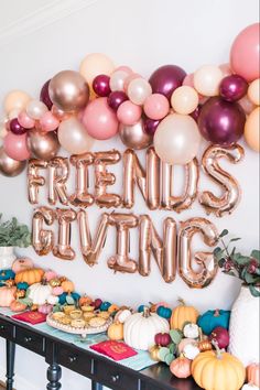 a table topped with lots of balloons next to a sign that says friends giving on it