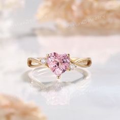 a pink heart shaped ring with three diamonds