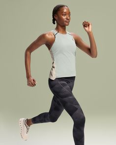 a woman is running while wearing a tank top and leggings