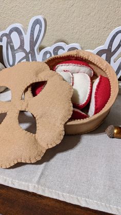 a wooden box filled with red and white items on top of a table next to scissors