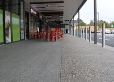 an empty sidewalk with red chairs and tables