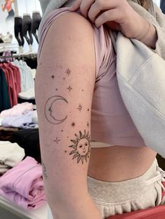 a woman with a sun and moon tattoo on her left arm is looking at the camera