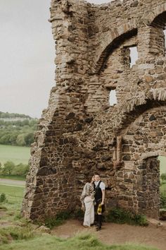 a bride and groom standing in front of an old castle