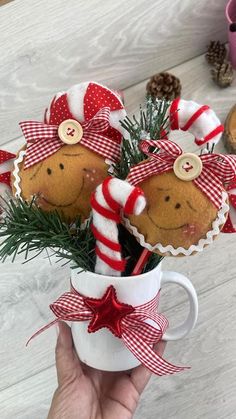 a person holding a cup filled with cookies and candy canes on top of a table