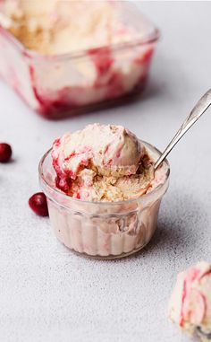 an ice cream sundae with cranberry sauce in a glass bowl and two spoons