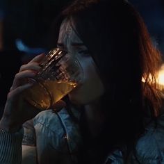 a woman drinking from a glass in the dark