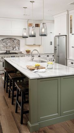 a large kitchen island with stools in front of it and lights hanging from the ceiling