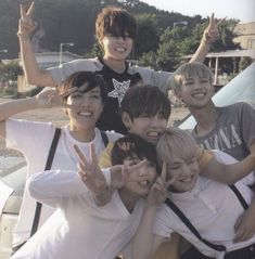 a group of young men standing next to each other on top of a sandy beach