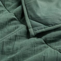 an unmade bed with green sheets and pillows