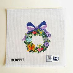 a cross - stitch christmas card with a wreath on the front and bow at the center