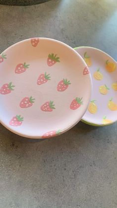 two plates with strawberries on them sitting on a counter top next to each other