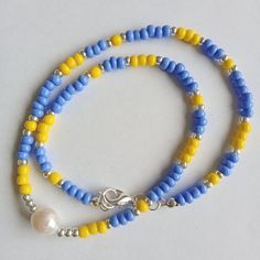 This minimalist handmade dainty necklace is made of yellow and blue opaque beads, silver glass seed beads with natural freshwater pearl bead. Stylish beaded necklace  is a perfect addition to summer beach outfits and it's a beautiful handmade gift for women and girls. Similar chokers are available in different color combinations. The length of the necklace is 40,5 cm.  All necklace metal findings are nickel-free and silver plated. At the request the length of necklace can be changed.  Please, pay attention to FAQs and if you have any question, don't hesitate to ask.  Thank you for visiting my shop! Blue Beaded Dainty Necklace, Dainty Blue Necklaces For Summer, Dainty Blue Necklace With Tiny Beads, Dainty Blue Beaded Necklace, Minimalist Blue Beads For Gift, Blue Dainty Necklace With Colorful Beads, Dainty Blue Necklace With Colorful Beads, Minimalist Blue Round Bead Necklace, Dainty Handmade Blue Beaded Necklace