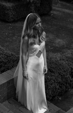 a woman in a wedding dress is standing outside