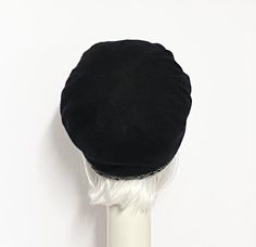 a black hat on top of a white pole