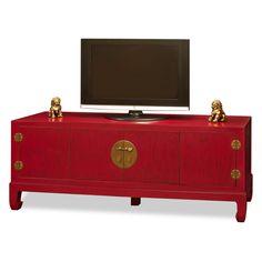 a red entertainment center with two golden lions on the doors and a flat screen tv