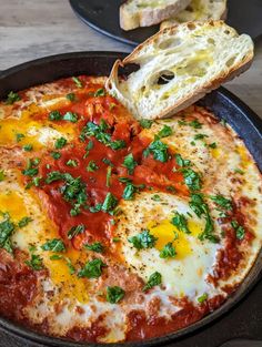 an omelet is being served in a skillet with bread on the side