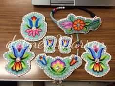 embroidered flowers and butterflies are displayed on a table next to a laptop computer with cords