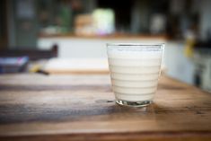 a glass filled with liquid sitting on top of a wooden table