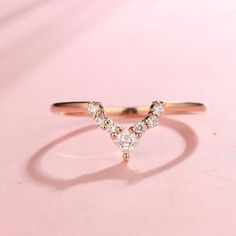 a gold ring with three diamonds on it, sitting on a pink surface in front of a white background