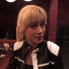 a woman with blonde hair wearing a black jacket and white collared shirt in a restaurant