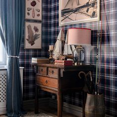 a desk with a lamp and pictures on the wall next to an old dresser in front of a window