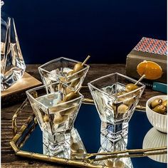 three glasses with olives in them sitting on a tray