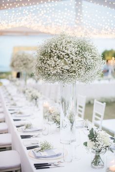 the table is set with white flowers and place settings for guests to sit down at