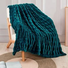 a blanket that is on top of a chair next to a rug and a book