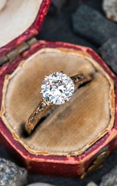 a diamond ring sitting on top of an old wooden box with velvet lining around it