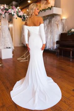 a woman in a white wedding dress standing on a wooden floor with her back to the camera