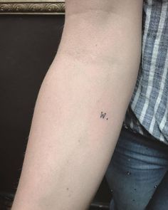 a woman's arm with the word w on it and a small letter tattoo