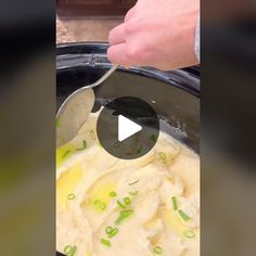 a person is spooning mashed potatoes into a crock pot with green onions