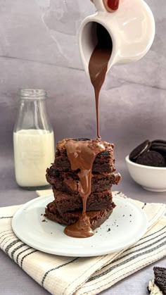 a stack of chocolate brownies being drizzled with chocolate sauce