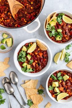 three bowls filled with chili, corn and avocado