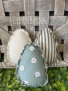 two decorative pillows sitting on top of a wooden table next to a basket with an egg in it