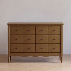 a wooden dresser sitting on top of a hard wood floor next to a white wall