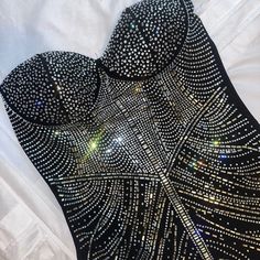 a black and silver dress with lots of sequins on the back, sitting on top of a white sheet