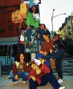 a group of people sitting on top of a street sign next to eachother