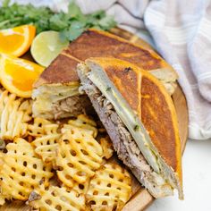 a sandwich cut in half on top of a wooden cutting board with cheesy waffles