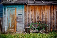 a green bicycle parked in front of a wooden building