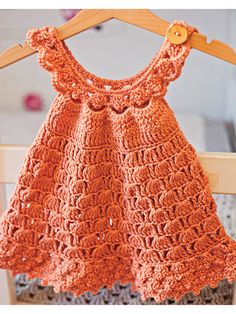 an orange crocheted dress hanging on a wooden hanger