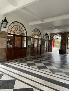 an empty hallway with several doors and windows on either side of the entrance to another building